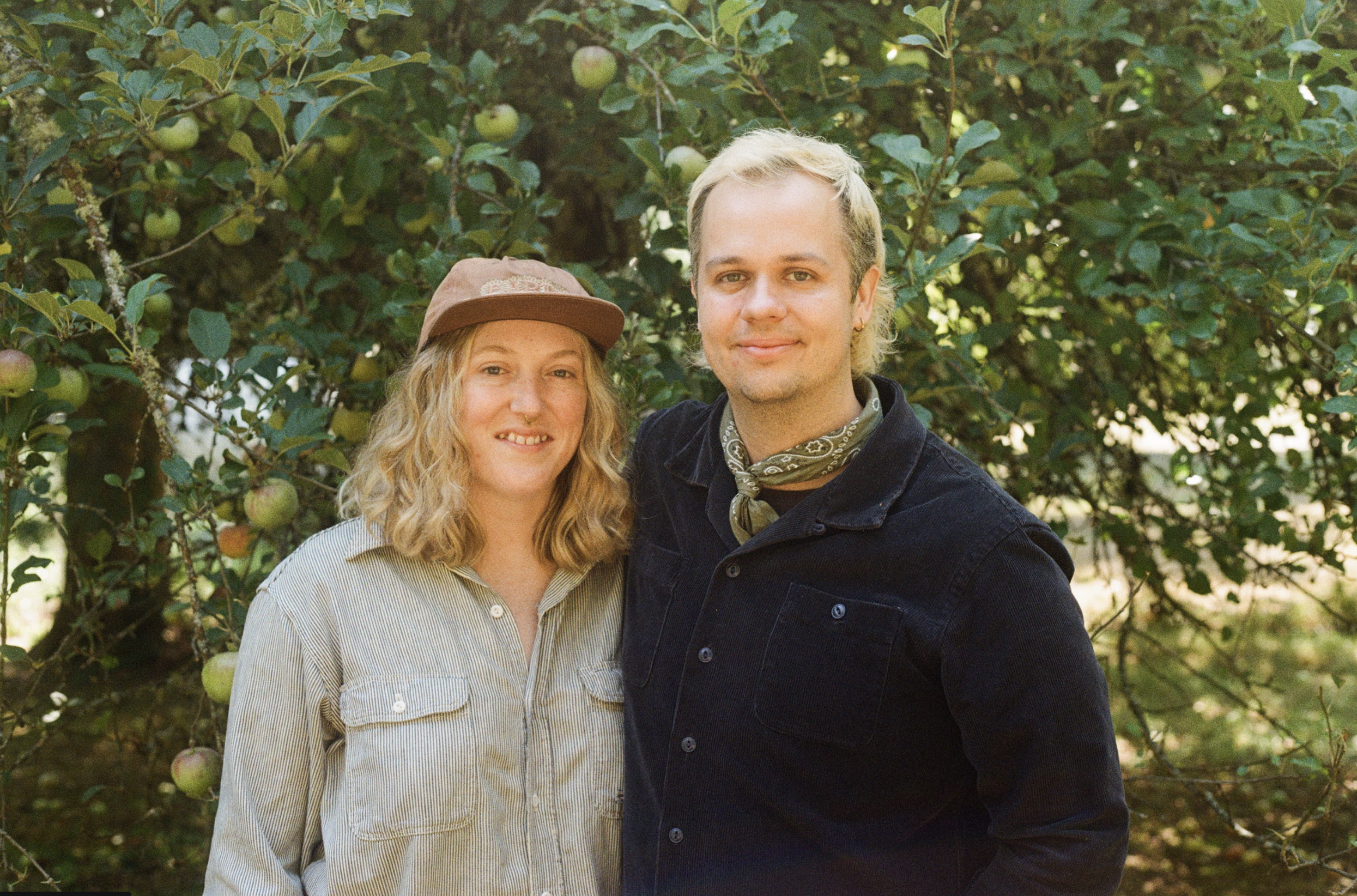 Anna and Sam standing in front of an apple tree
